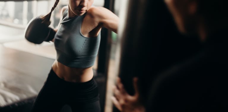 Fit woman in sportswear practicing boxing indoors with focus and power.