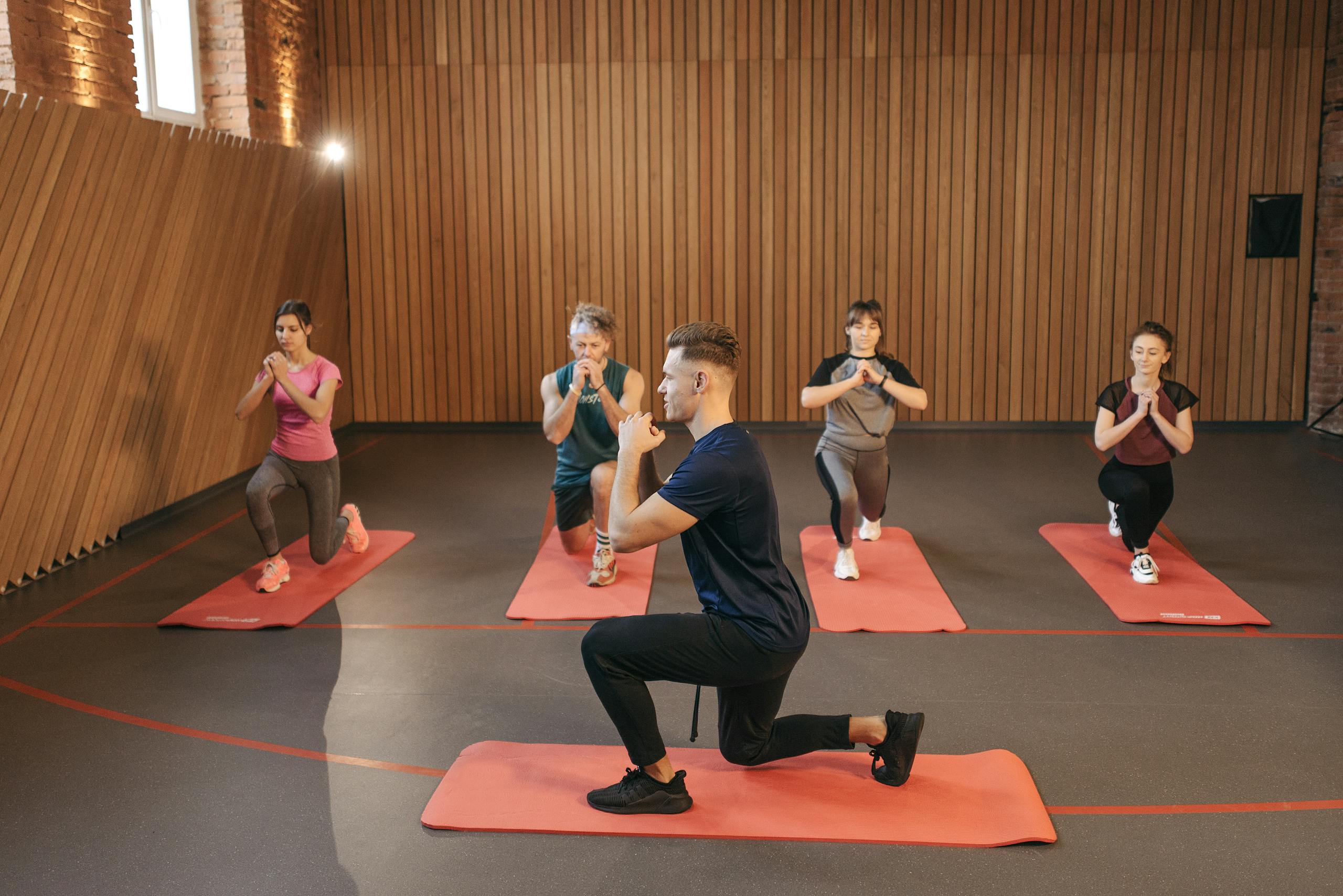 A diverse group practicing fitness and yoga exercises indoors with mats.
