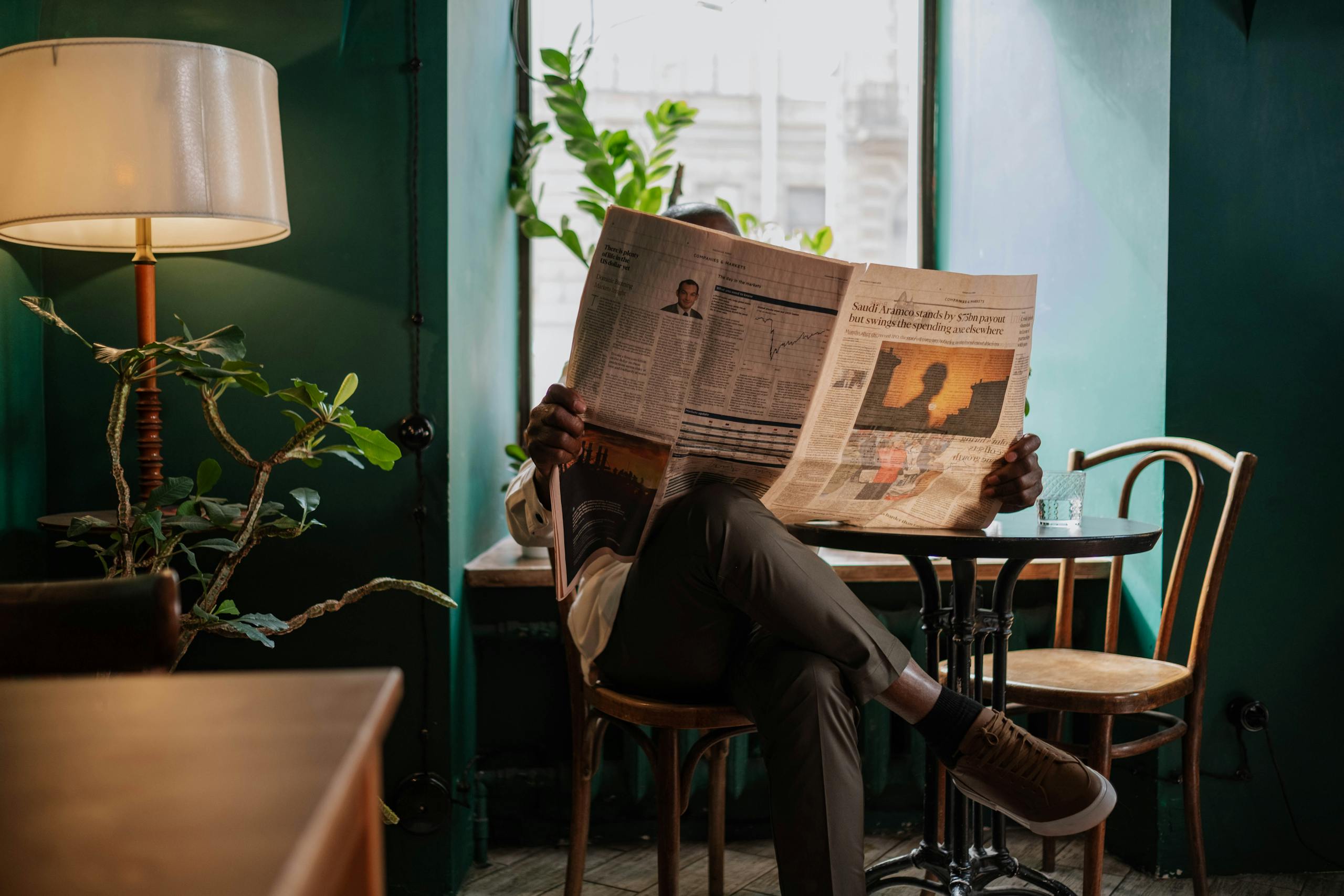 A man sits in a cozy café corner, enjoying a newspaper and relaxed ambiance.