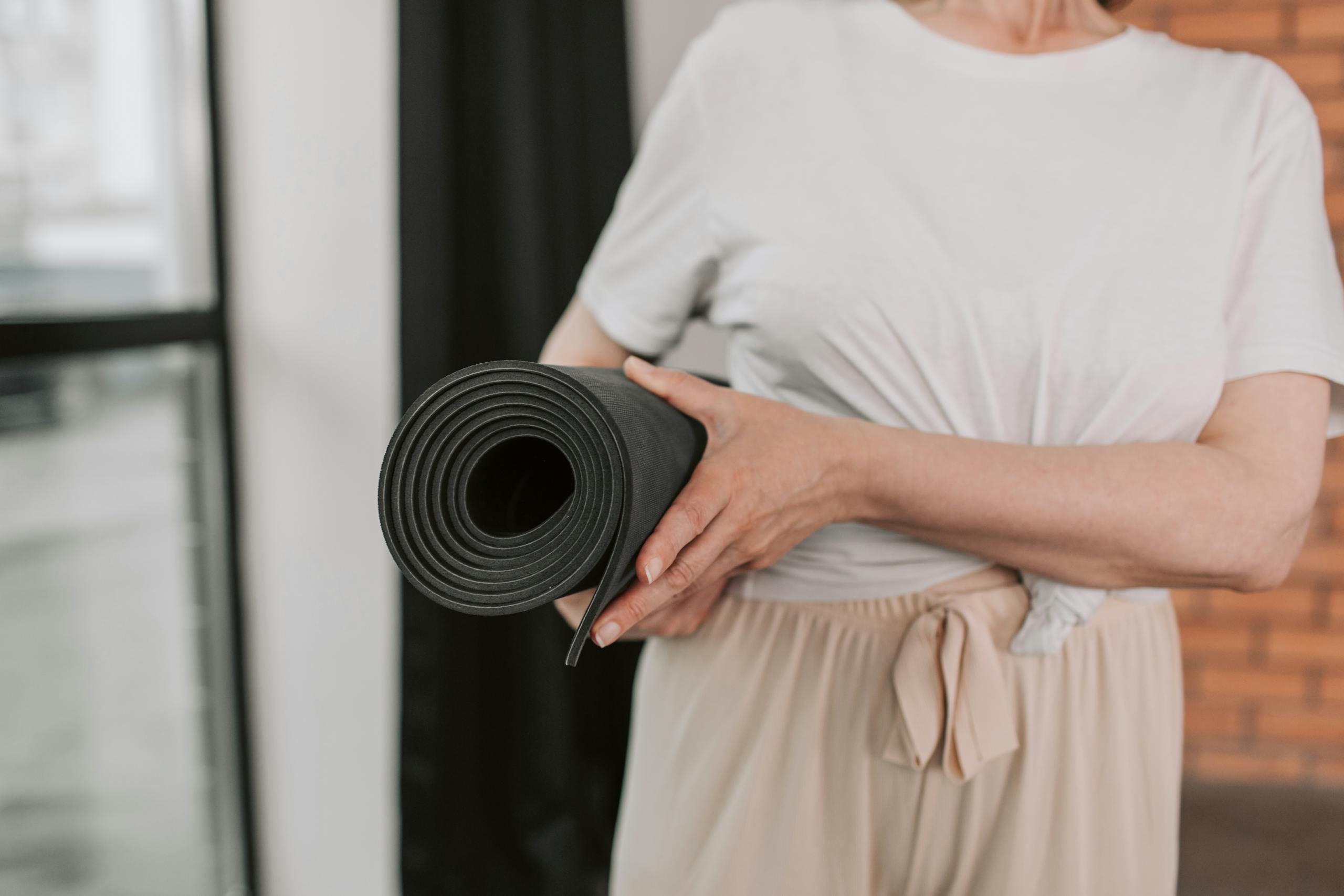 Close-up of a senior woman holding a yoga mat, ready for a session in a modern studio.